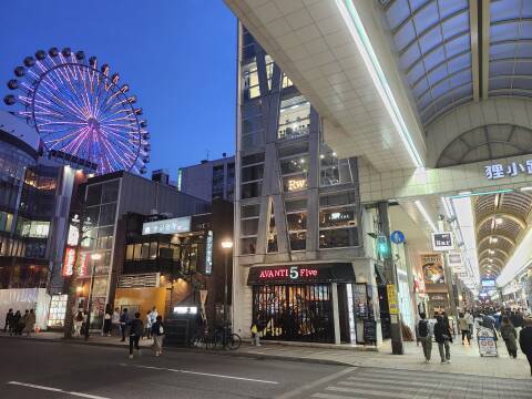 Tanukikoji, a long covered shopping street in Sapporo at dusk, colorful ferris wheel in the Susukino entertainment district in the background.