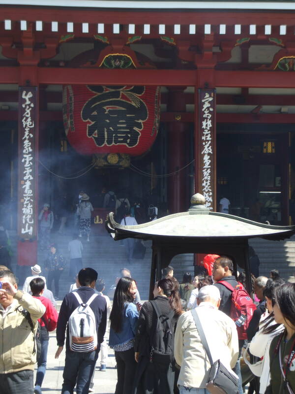People waving the incense smoke, 'the breath of the gods', over themselves for purification at the incense burner at Sensō-ji in Asakusa district of Tōkyō.