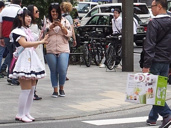 Girl wearing a maid costume in Akihabara handing out fliers for a maid café.