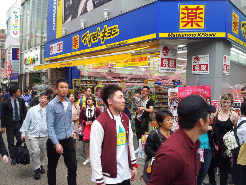 People walk past the Matsumoto KiYoshi shop of pastel colors on Takeshita-dori or Takeshita Street in Harajuku.