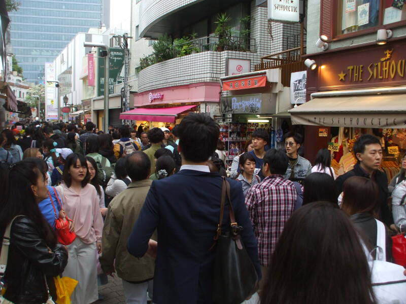 Crowds of people walk past shops on Takeshita-dori or Takeshita Street in Harajuku.