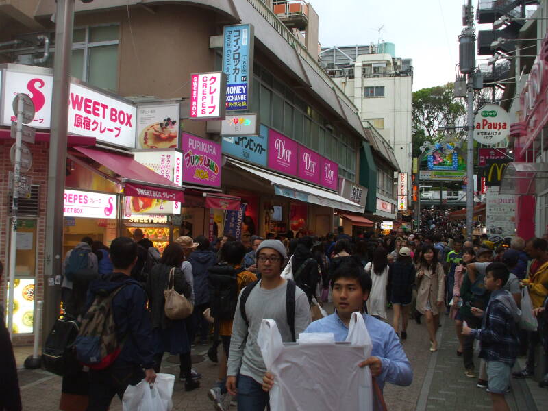 Crowds of people walk past shops on Takeshita-dori or Takeshita Street in Harajuku.