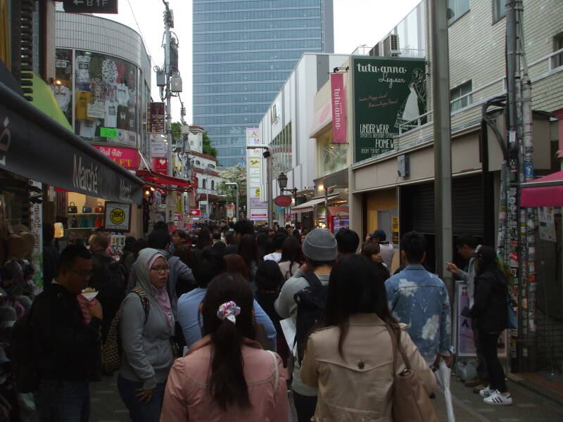 Crowds of people walk past shops on Takeshita-dori or Takeshita Street in Harajuku.