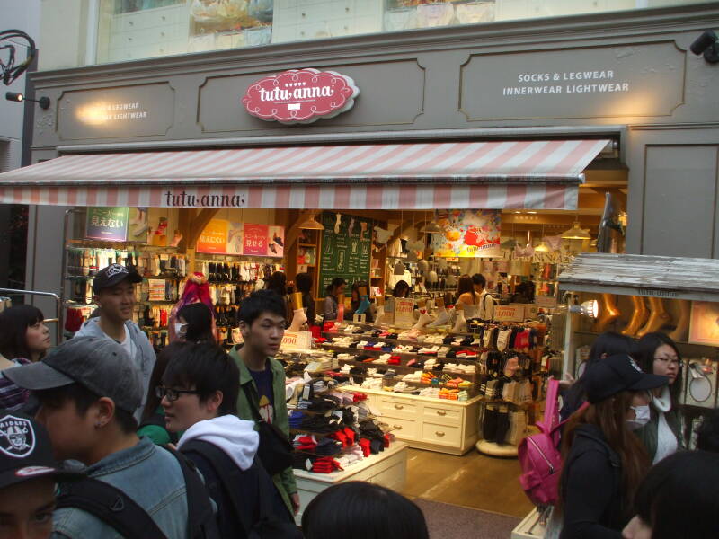 Crowds of people walk past shops on Takeshita-dori or Takeshita Street in Harajuku.