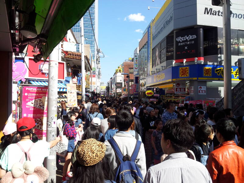 People walk past the Matsumoto KiYoshi shop of pastel colors on Takeshita-dori or Takeshita Street in Harajuku.