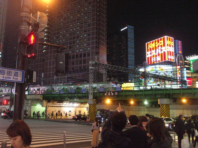 View east on Yasukuni Dōri from northwest corner of Omoide Yokochō in Shinjuku, in Tōkyō, as a train arrives at Shinjuku