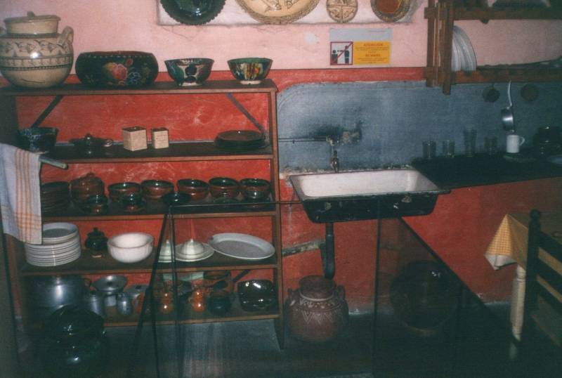 Leon Trotsky's kitchen: a metal sink and washboard, a set of shelves, and dishes and bowls.