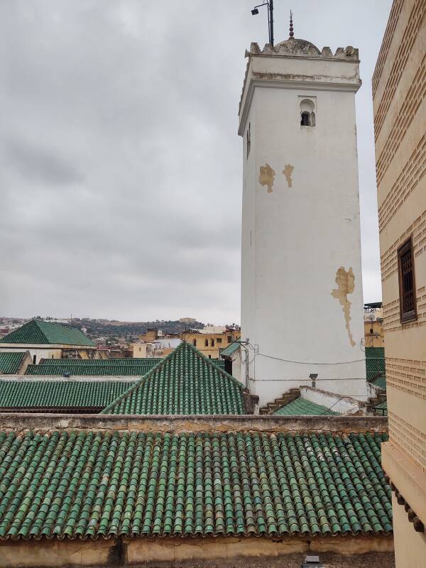 View out of window of a student room in dormitory of al-Attarine Madrasa, showing a minaret and mosque roofs, in Fez el Bali medina along Tala'a Sghira.