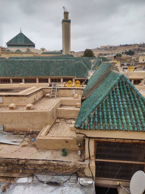 View out of window of a student room in dormitory of al-Attarine Madrasa, showing a minaret and mosque roofs, in Fez el Bali medina along Tala'a Sghira.
