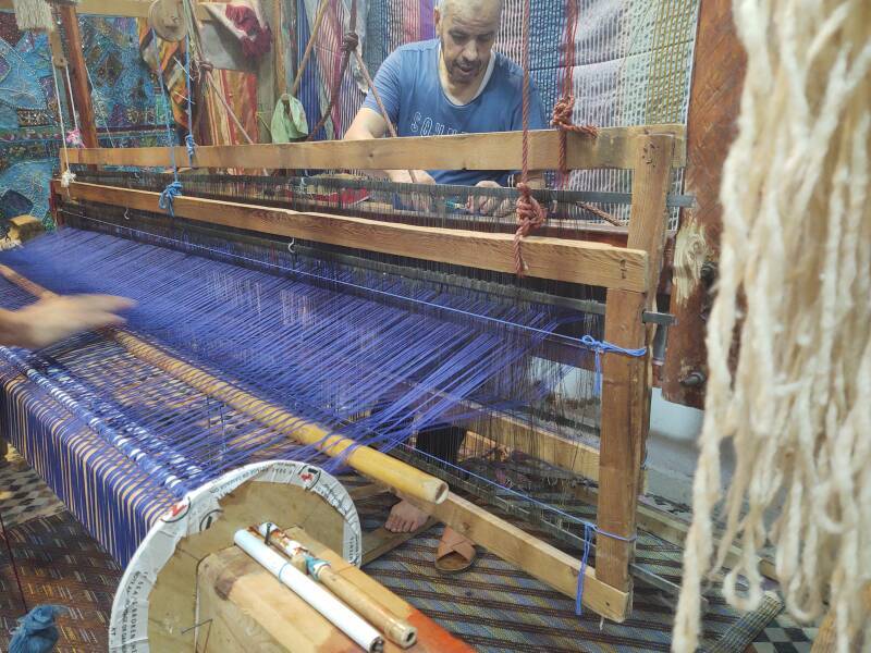 Man operating a loom, weaving cloth in Fez el Bali medina along Tala'a Sghira.