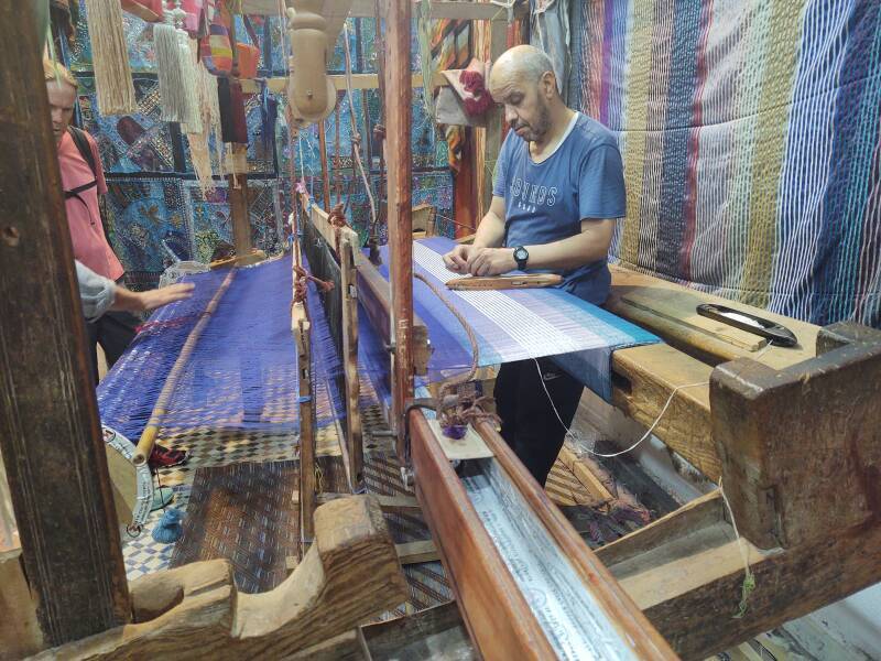 Man operating a loom, weaving cloth in Fez el Bali medina along Tala'a Sghira.
