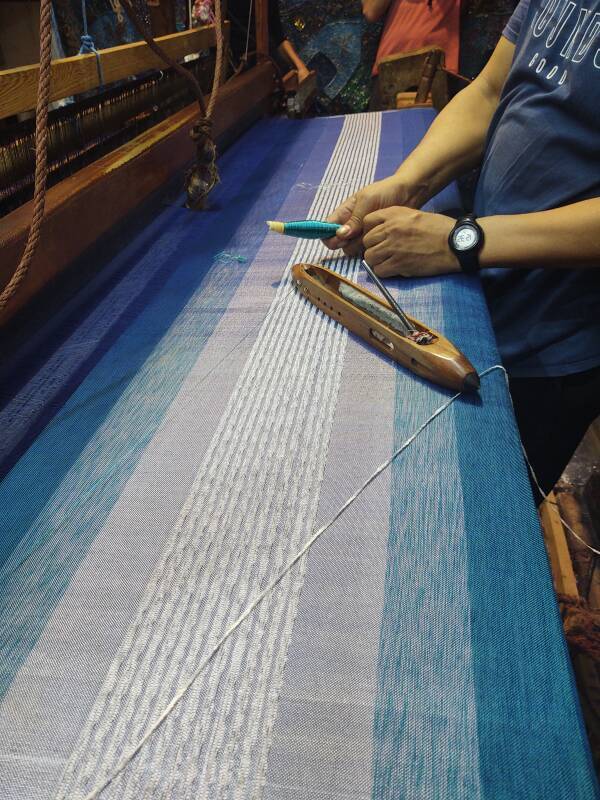 Man operating a loom, weaving cloth in Fez el Bali medina along Tala'a Sghira.