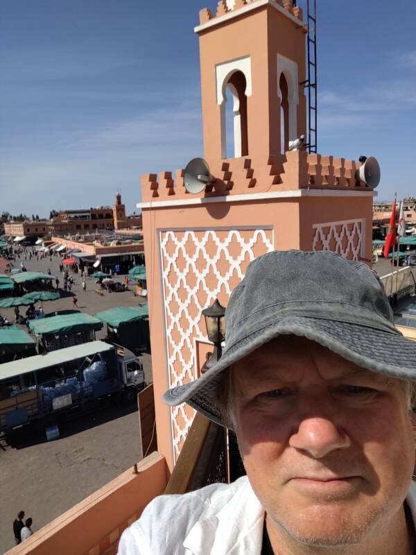Bob with a minaret behind him, on a balcony overlooking Sāḥat Jāmi' al-Fanā', or The Mosque at the End of the World, in central Marrakech.