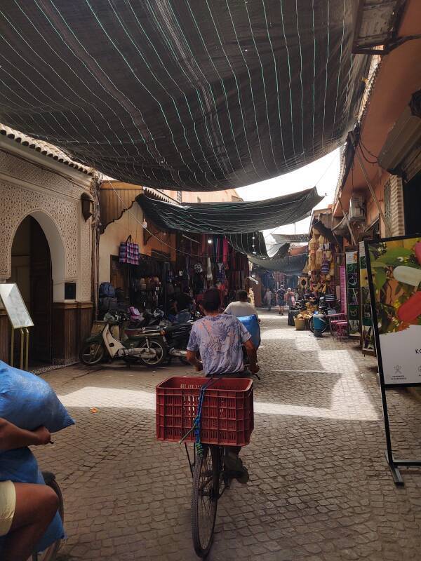 Man riding a bicycle under a fabric souq cover in the medina in Marrakech.