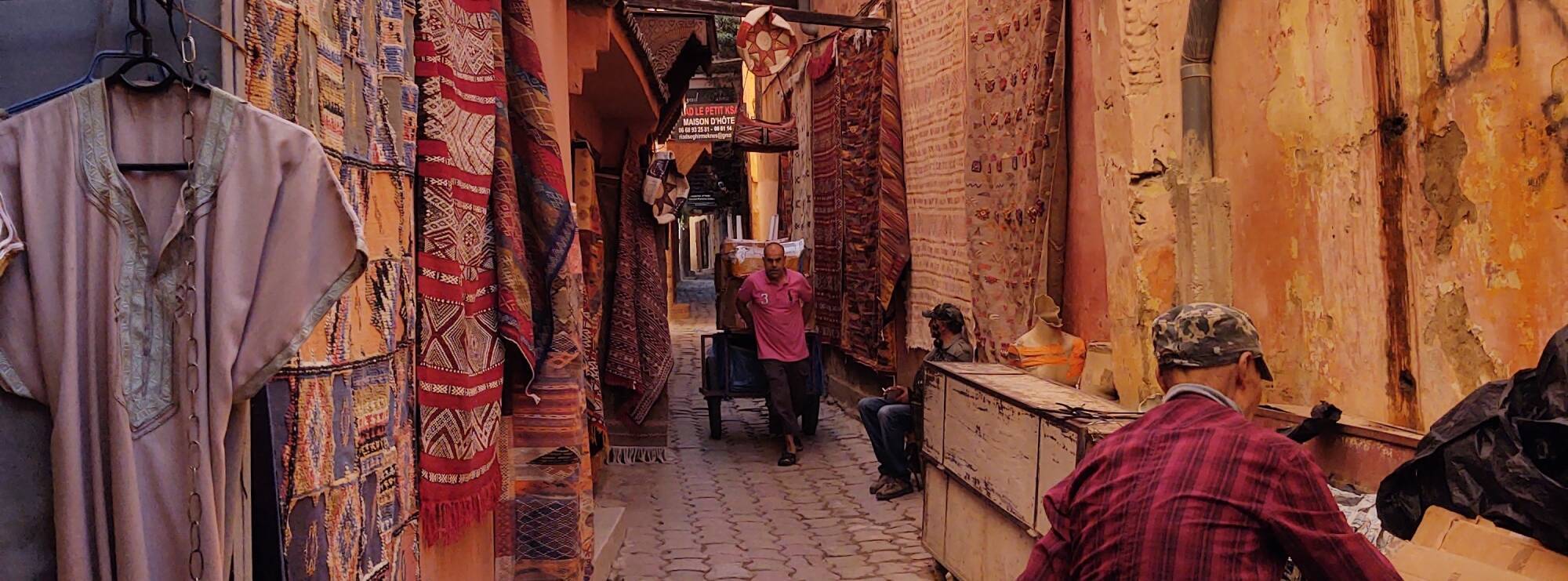 A man pulls a handcart down a narrow lane through the medina of Meknès.
