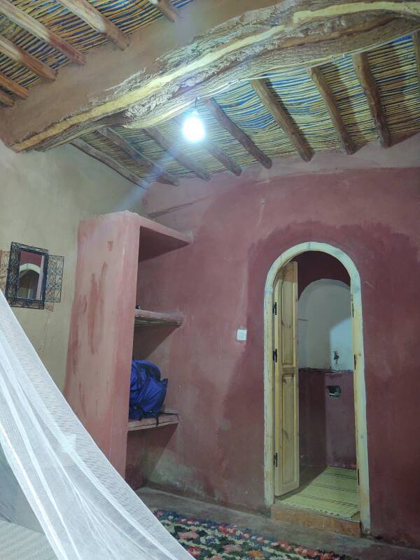 Mosquito net, carpet, shelves, rattan roof, and door to bathroom in my room.