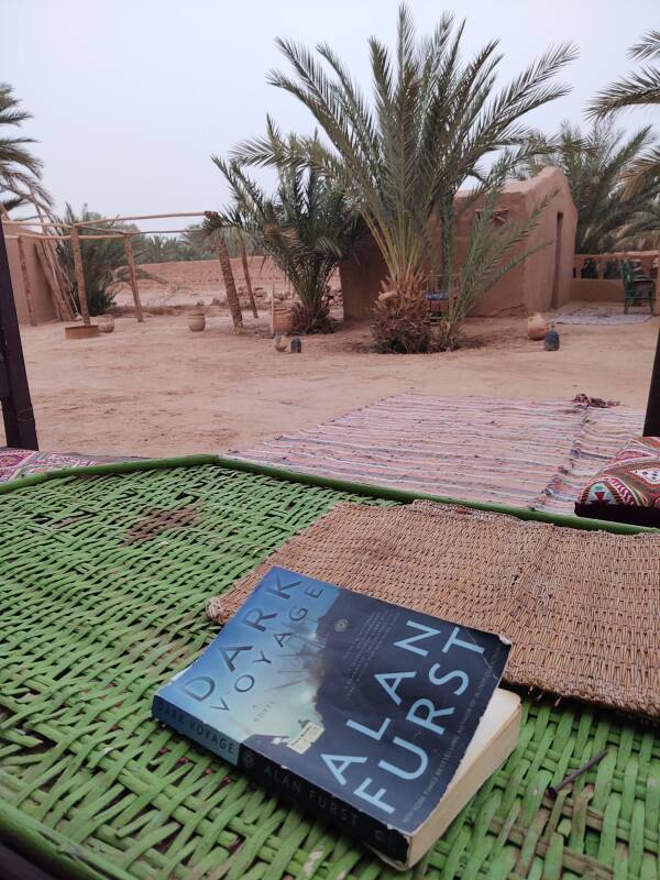 Alan Furst novel on the table, sitting in the shade in a courtyard.