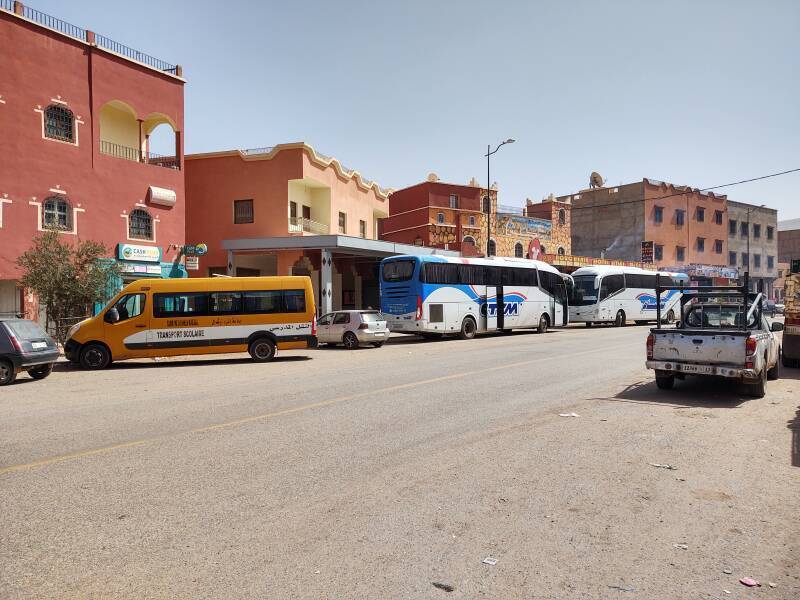 Two inter-city buses and a school bus on the highway through Agouim.