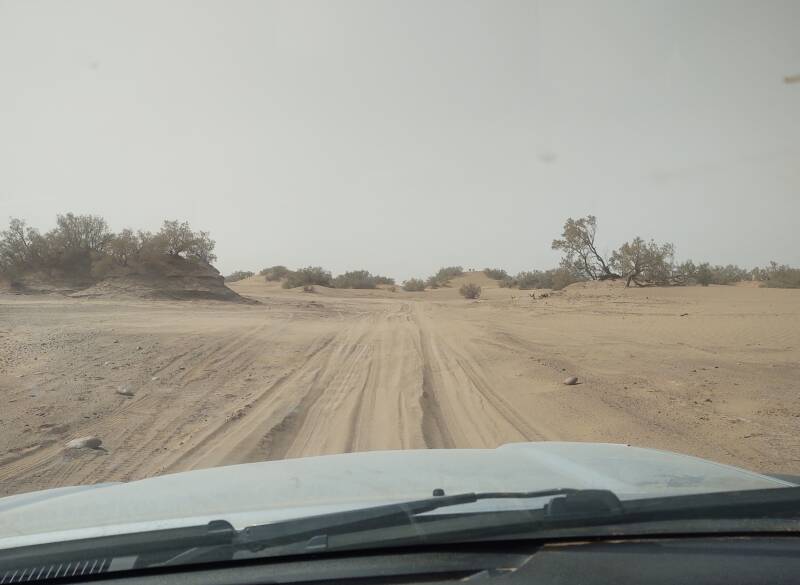 Looking out through the windshield at the sandy track in the desert outside M'Hamid.