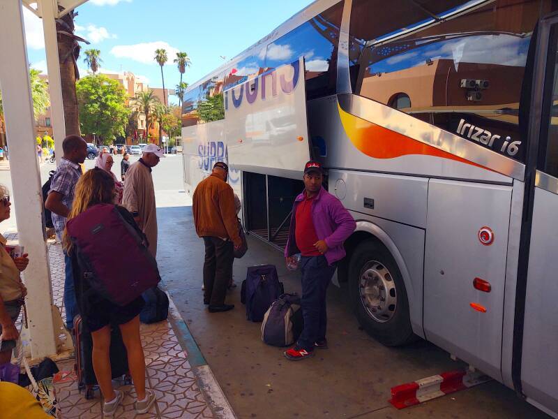 Loading passengers and bags into the bus from Marrakech to Zagora.
