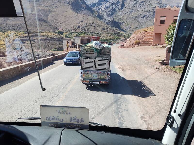 Heavily loaded truck with sheep on top enters a small town in the Atlas Mountains.