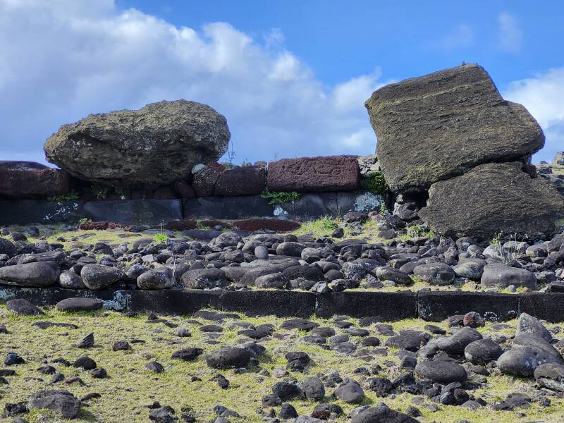 Red scoria with petroglyphs between two toppled mo'ai at Akahaŋa.