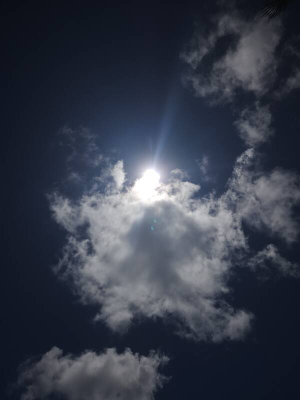 Partial phase of annular solar eclipse with crescent lens flares, seen in Hanga Roa, Rapa Nui.