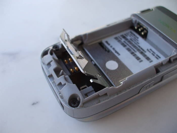 SIM card carrier being lifted inside the battery compartment of a Nokia 6086 GSM phone.