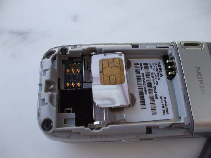 SIM card ready for replacement inside the battery compartment of a Nokia 6086 GSM phone.