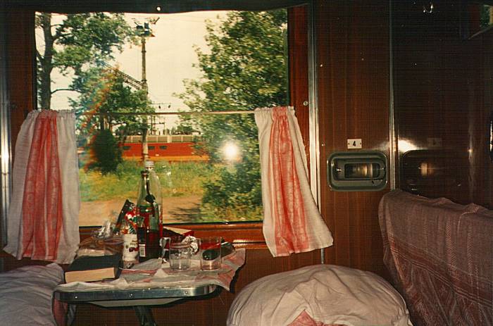 Interior of a Russian sleeper car with bottles and books by the window.