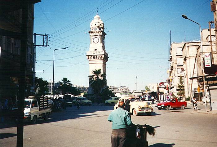 Clock tower, street sweeper, and classic American car on Al-Maari street near the Russian and Armenian bazaar in Aleppo, Syria.