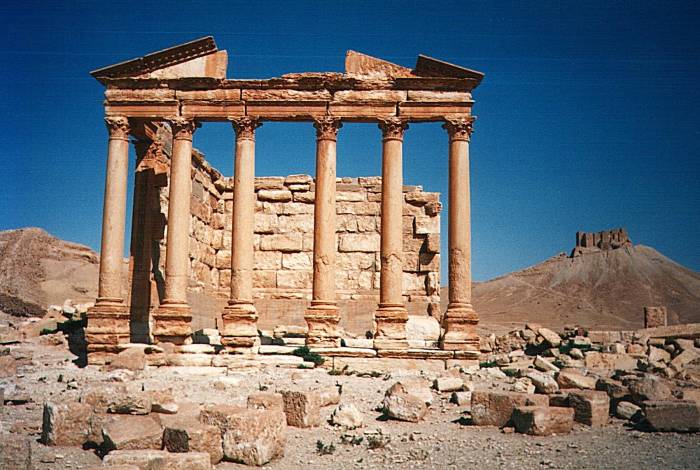A temple and the hilltop fortress Qala'at ibn Maan in the background, at Palmyra (Tadmur), Syria.