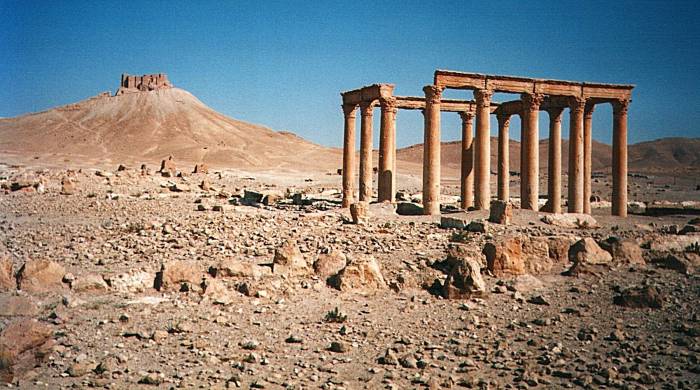 A columned structure at Palmyra (Tadmur), Syria, with the hilltop fortress in the distance.
