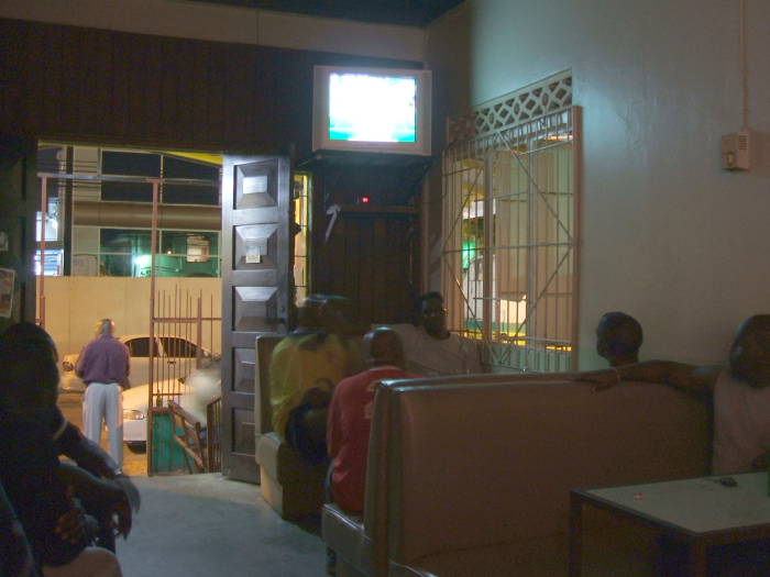 Nice small local pub in Trinidad.  Locals sit in the booths and watching television, a man stands in the street.