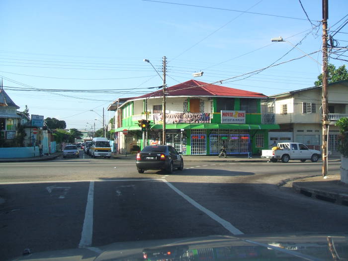 Driving down the street in Trinidad:  A car turns right in front of a brightly colored restaurant.