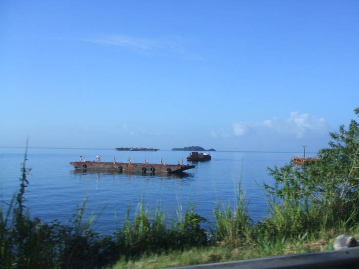Looking across the Gulf of Paria off the coast of Trinidad, toward the coast of Venezuela.  Two barges in the foreground, small islands in the distance.