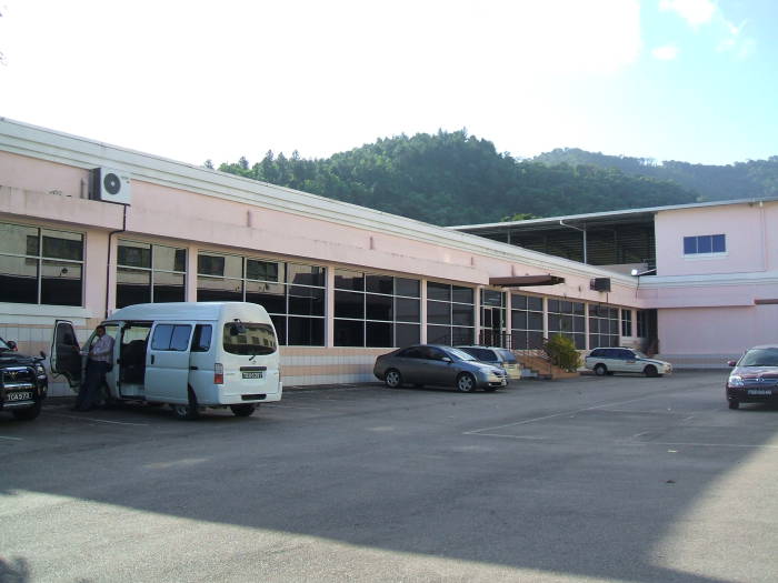 A simple industrial building: a parking lot and some windows.  The mountainous jungle is beyond.
