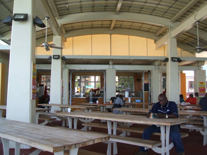 Bake and Shark breakfast at the Breakfast Shed in Trinidad.  Some other diners at the tables under the large awning.