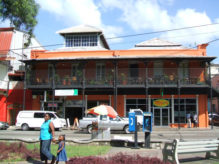 Downtown Port-of-Spain, Trinidad: Two shops on ground level, balconies with tables and chairs above.