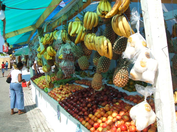 Downtown Port-of-Spain, Trinidad. Lots of brightly colored fruit for sale in the market: Bananas, pineapples, oranges, mangoes.