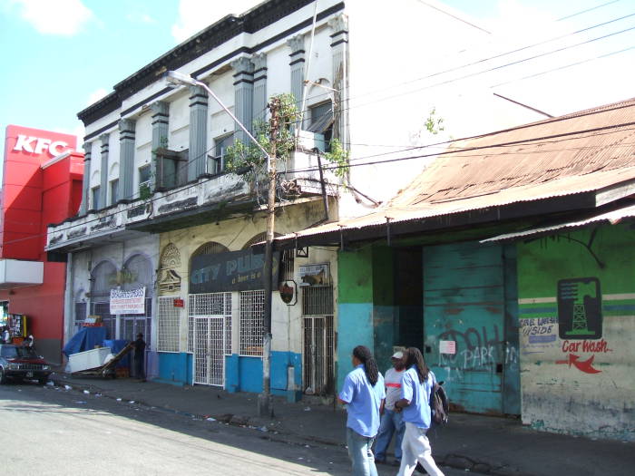 Downtown Port-of-Spain, Trinidad. Two men walk past an older building in need of some repair.
