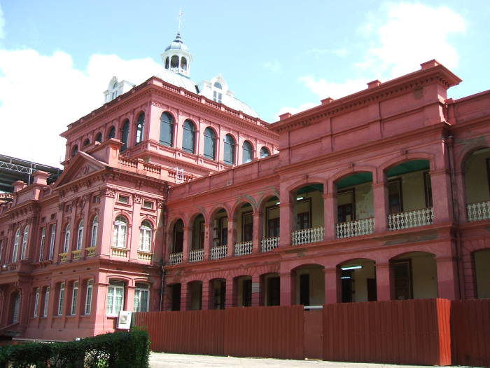 Red House, the Parliament in Trinidad.  A large red brick building with covered balconies and porticoes.