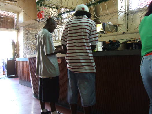 Having a casual lime!  Hanging out with the locals in a bar in downtown Port-of-Spain, Trinidad.  Two men order drinks at the bar.