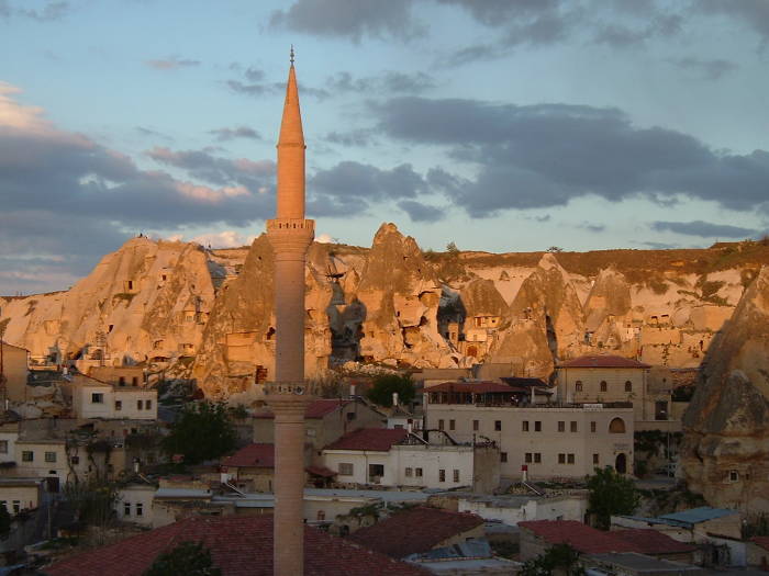 Minaret lit by sunset, view over rock towers in Göreme, in Cappadocia, Turkey.
