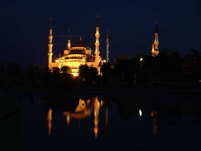 Blue mosque or Sultanahmet Cami, in Istanbul, with its six minarets and many domes.  Nighttime view with reflecting pool.