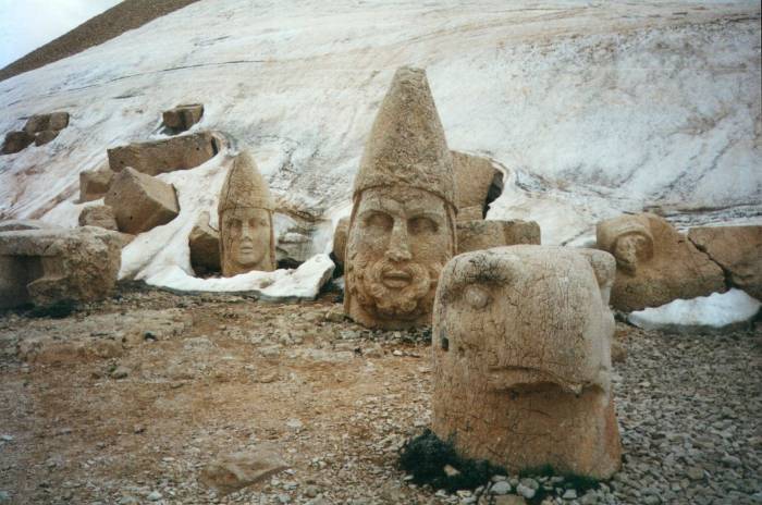 Large stone heads emerging from the snow on the summit of Nemrut Dağı.