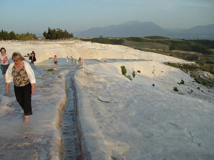 Women walking barefoot across the white flowstone formations at Pamukkale.