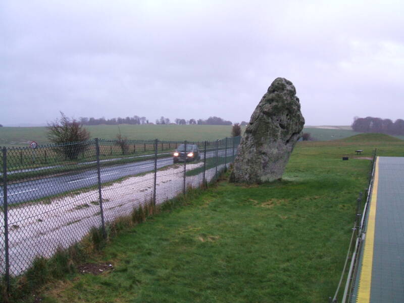 Stonehenge megalith alongside a narrow road.