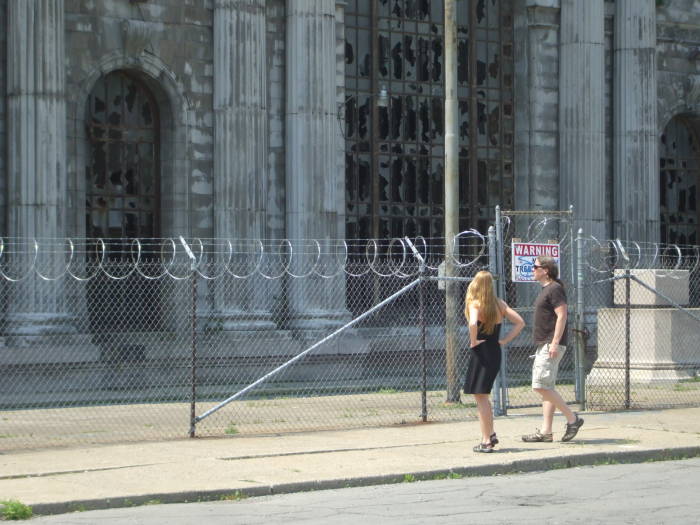 Two visitors looking at Detroit's Michigan Central Station.