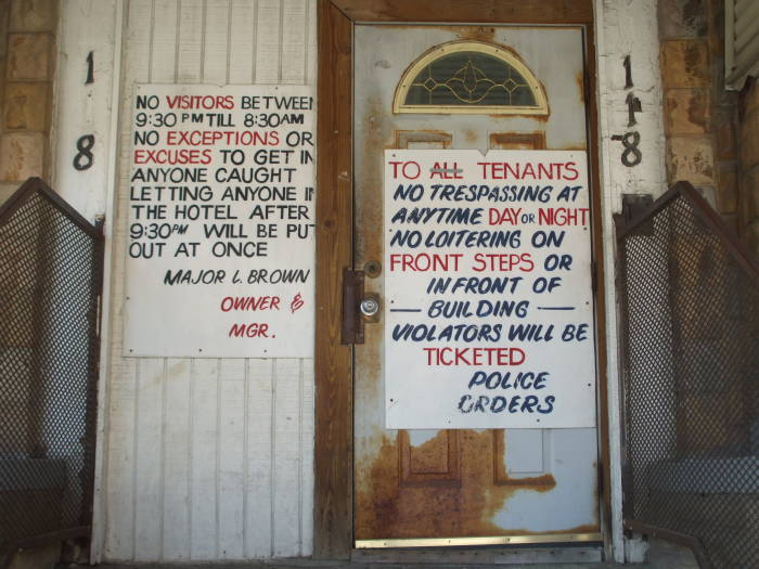 Adamant signs on the entry of the Wright Hotel at 118 Elizabeth near Park: 'NO VISITORS BETWEEN 9:30 PM TILL 8:30 AM.  NO EXCEPTIONS OR EXCUSES TO GET IN. ANYONE CAUGHT LETTING ANYONE IN THE HOTEL AFTER 9:30 PM WILL BE PUT OUT AT ONCE.  MAJOR L. BROWN, OWNER & MGR.  TO ALL TENANTS: NO TRESPASSING AT ANYTIME DAY OR NIGHT.  NO LOITERING ON FRONT STEPS OR IN FRONT OF BUILDING.  VIOLATORS WILL BE TICKETED.  POLICE ORDERS.